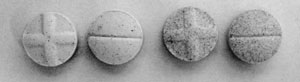 Photo of four circular PCP tablets showing shading and design differences.