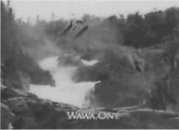 Exhibit K: A helicopter flying over water rushing down the side of a mountain with the caption 'WaWa, Ont.