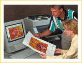 A man and woman reviewing a color print in front of a work station and printer