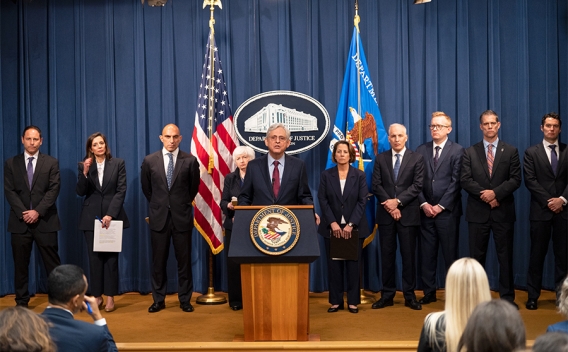 Attorney General Merrick B. Garland delivers remarks from a podium at the Department of Justice. He is joined by Department of Justice and federal government officials.