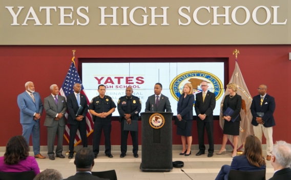 Assistant Attorney General Kenneth A. Polite delivers remarks from the podium of Jack Yates High School alongside law enforcement and community partners.