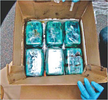 Photo showing a cardboard box containing six rectangular containers of ice methamphetamine.