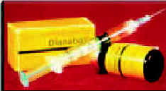 Photograph of a hypodermic needle resting on a small brown bottle in front of a prescription box.