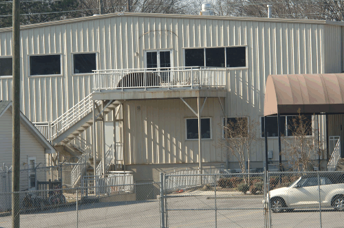A closeup photograph of a two-story steel building with a steel deck and staircase leading up from the ground to the second floor.