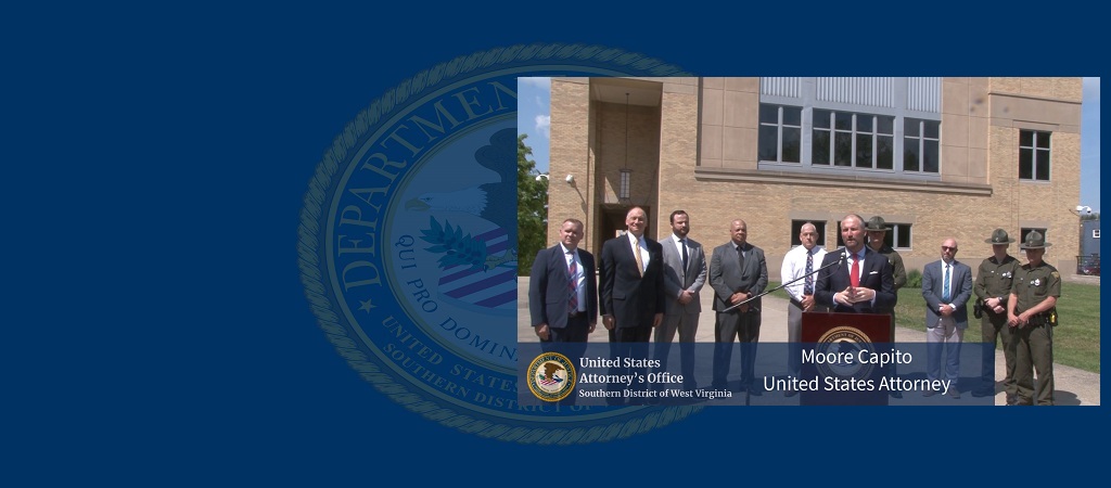 Photo of U.S. Attorney Moore Capito at the podium during an April 24, 2026, press conference in Beckley, West Virginia, with several individual and the federal courthouse in the background. 