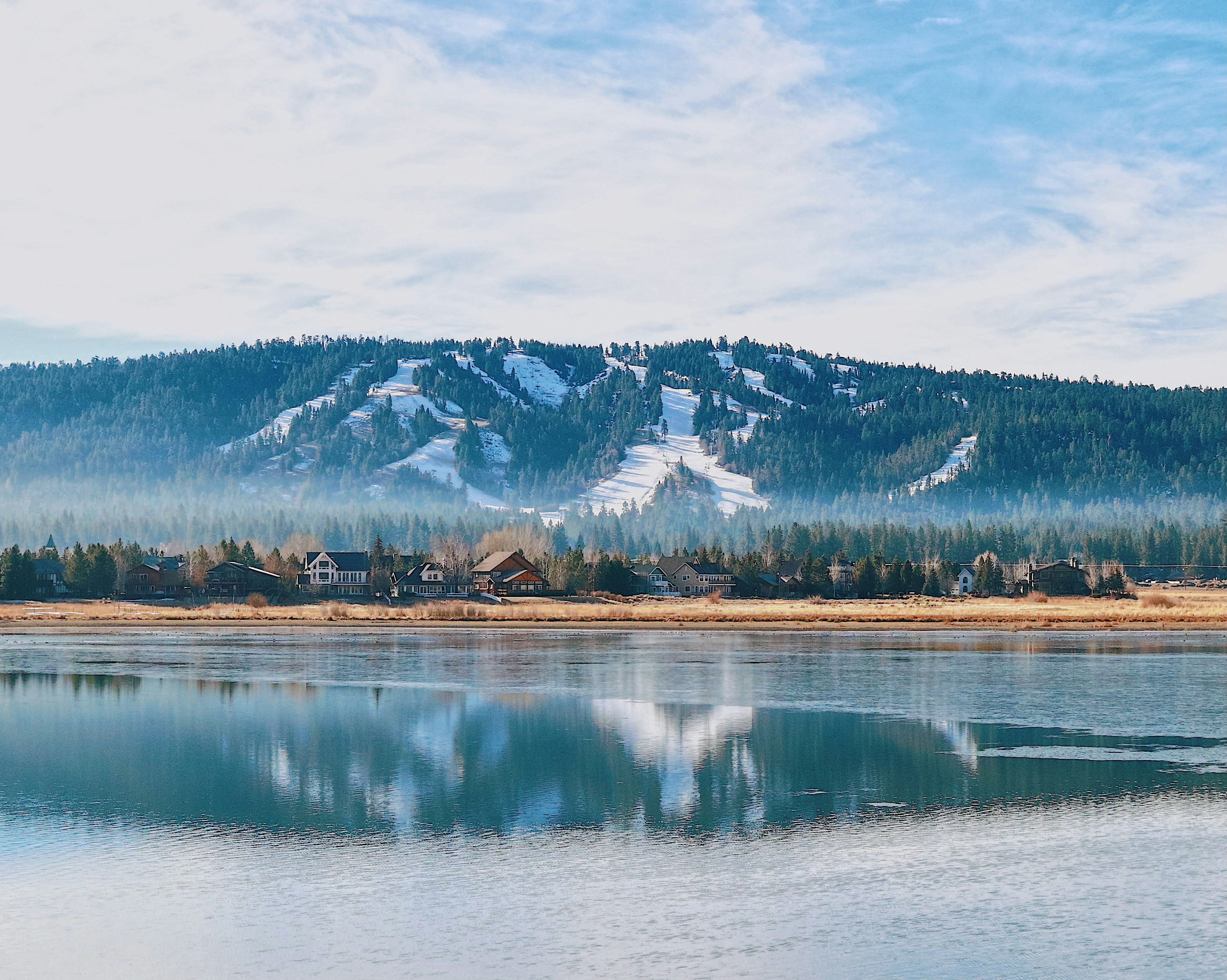 Images of Big Bear Lake in the foreground with homes and snowy mountains in the background