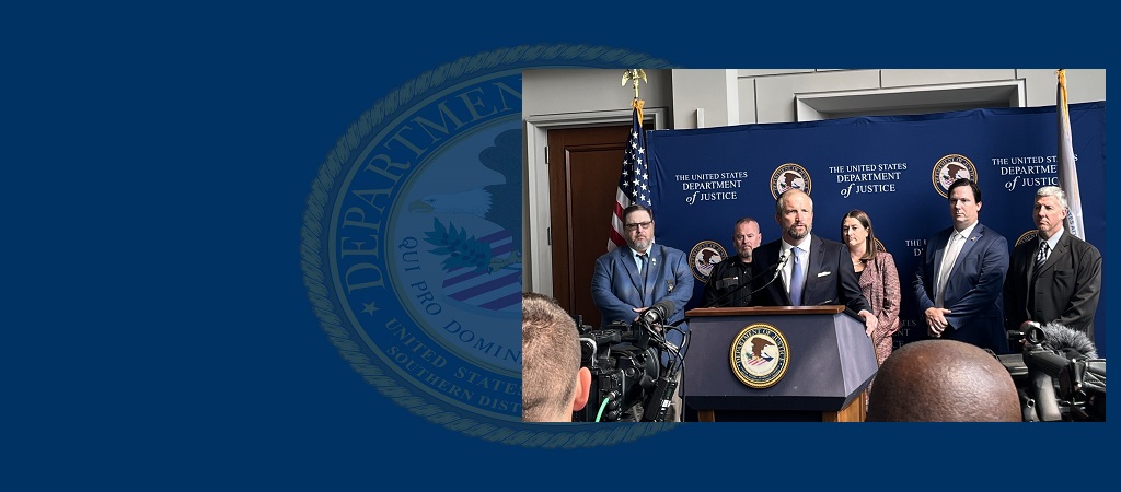 Photo of U.S. Attorney Moore Capito speaking at the podium during a press conference in Charleston, with several people standing behind him.