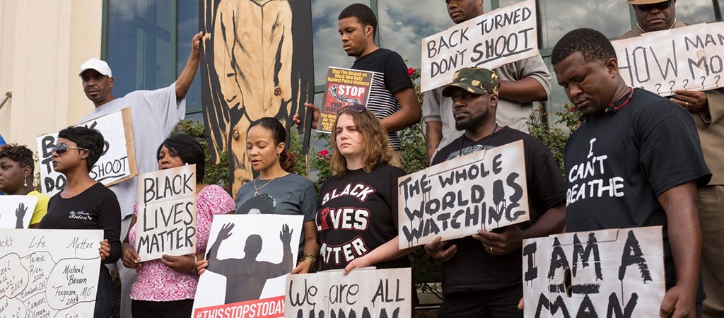 A group of community members gather to protest a police shooting against a Black man. 