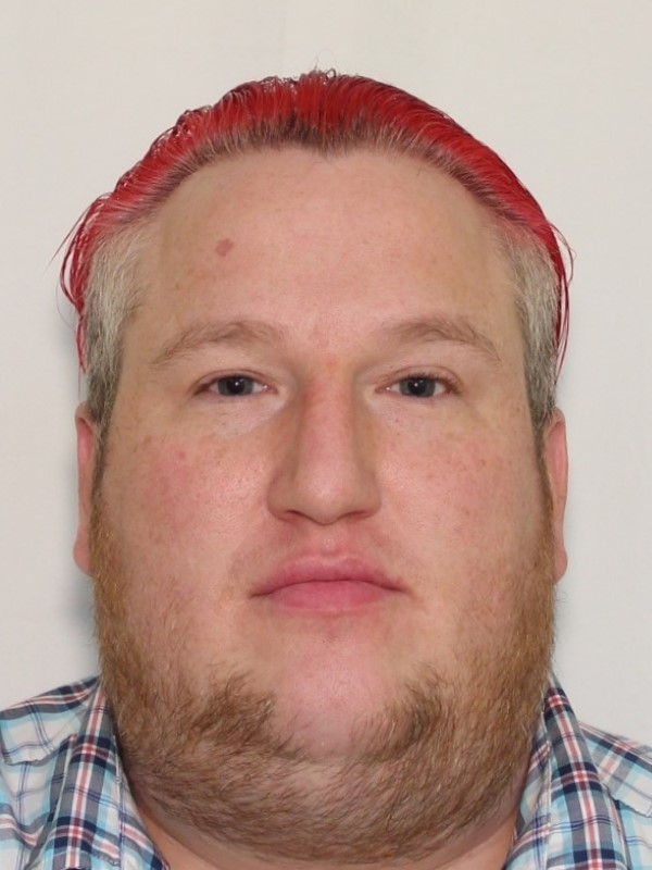 A photo of a man with red and blonde hair in a plaid shirt.