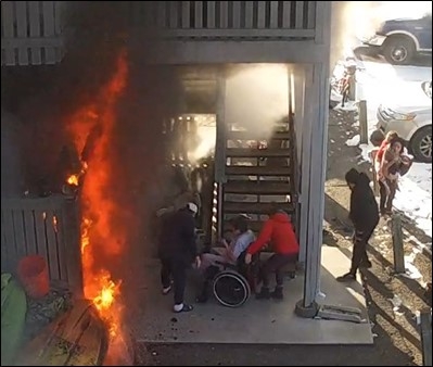 Apartment building on fire as people leave the building.