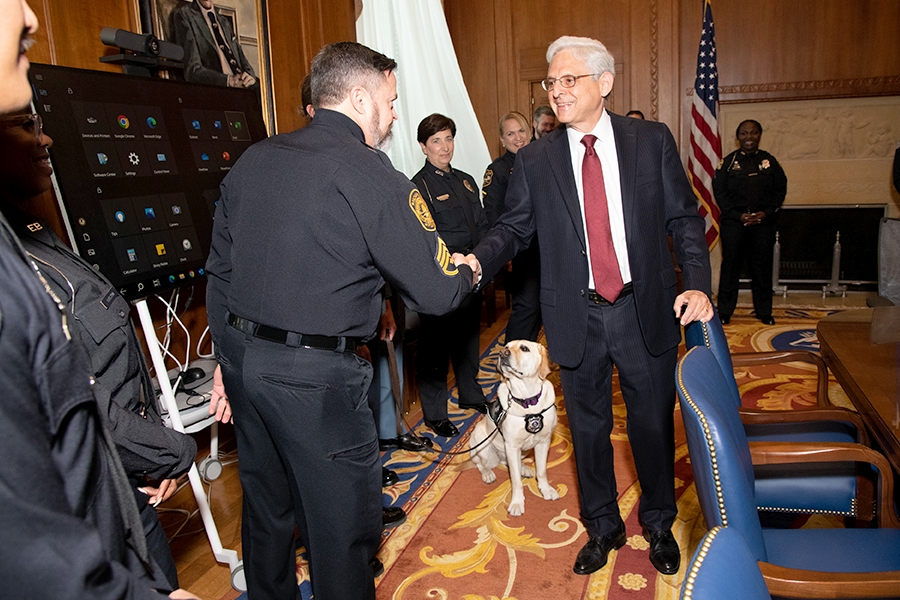 Attorney General Merrick B. Garland shakes hands with a police officer in the Attorney General’s conference room in the Department of Justice