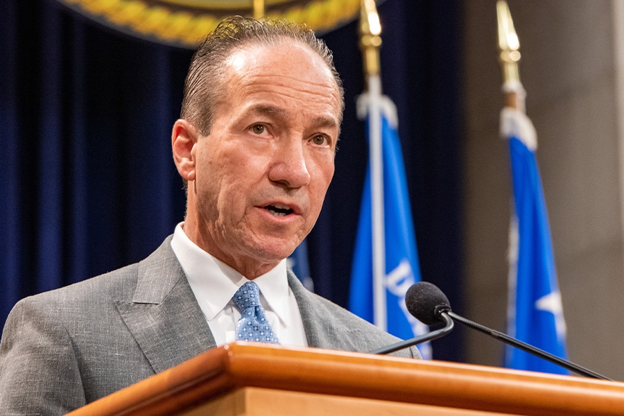 COPS Director Hugh T. Clements Jr. delivers remarks from a podium at the Department of Justice