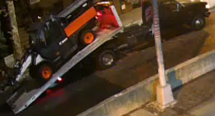 Photo showing the defendant using large trucks to steal utility vehicles