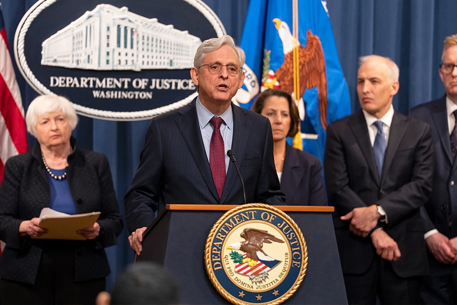 Attorney General Merrick B. Garland delivers remarks from a podium at the Department of Justice. He is joined by Department of Justice and federal government officials.