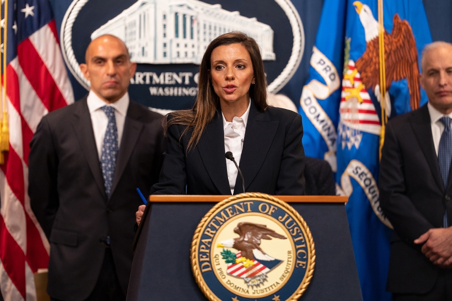Acting Assistant Attorney General Nicole M. Argentieri delivers remarks from a podium at the Department of Justice. To the left is Chairman Rostin Behnam of the Commodity Futures Trading Commission (CFTC), and to the right is Assistant Attorney General for National Security Matthew G. Olsen.