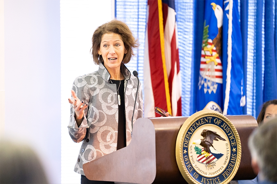 Assistant Attorney General for the Office of Justice Programs Amy Solomon delivers remarks from a podium at the Office of Justice Programs.