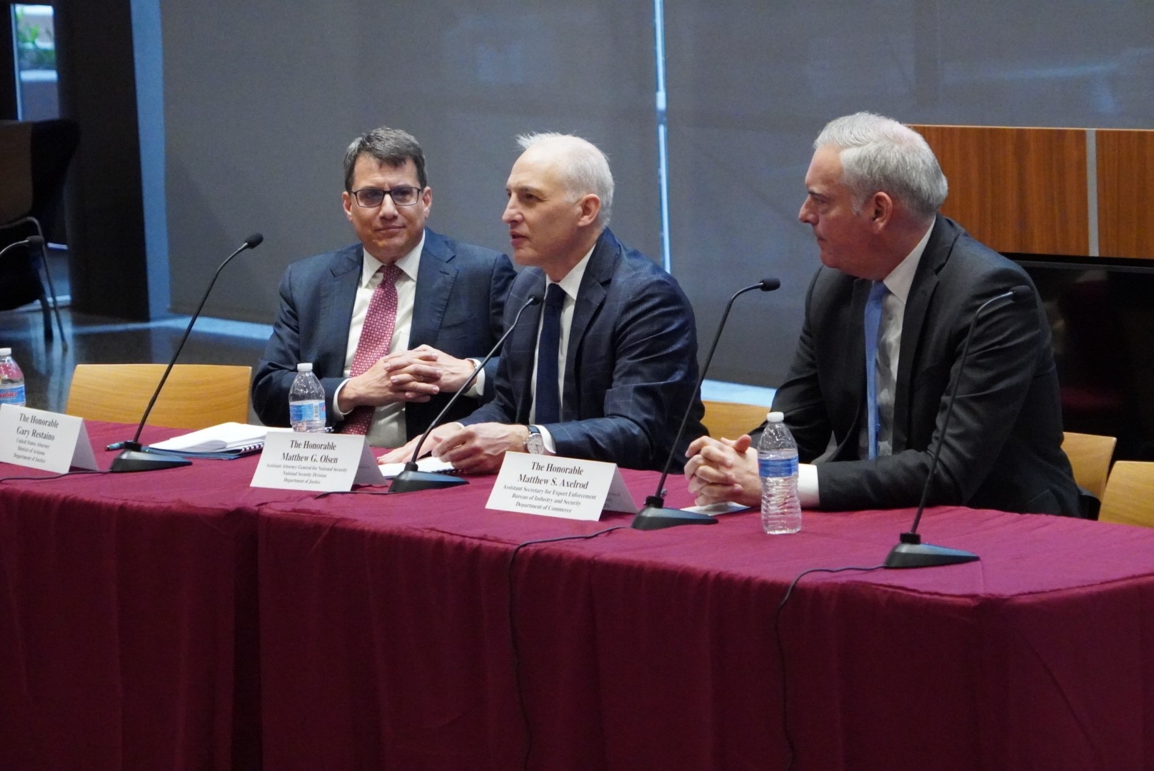 A group of three men sitting at a table with microphones.