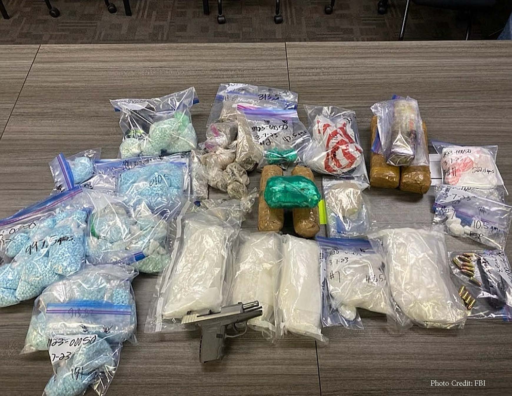 Drugs and handgun evidence displayed on a table 