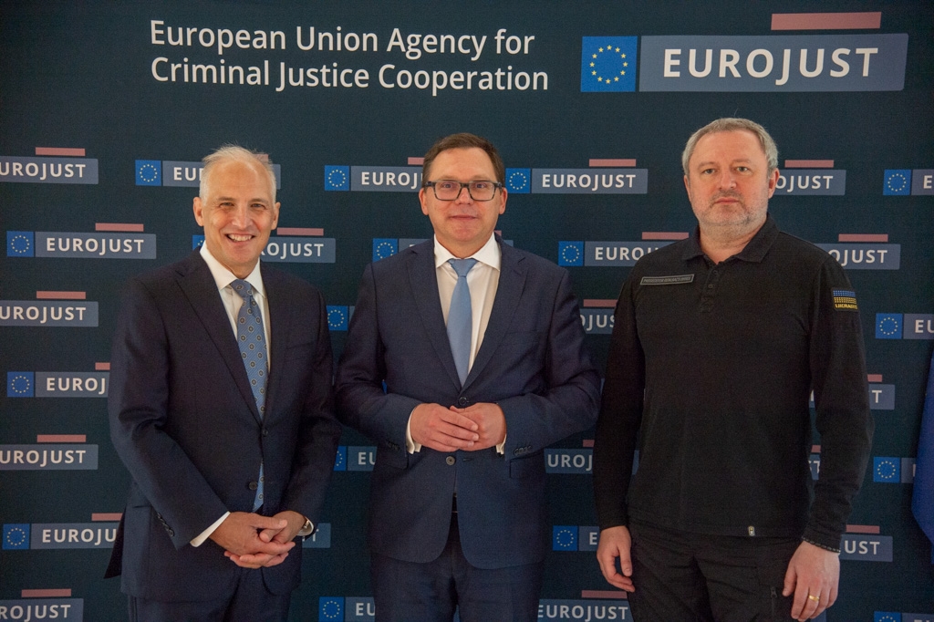 Three men standing side-by-side smiling.