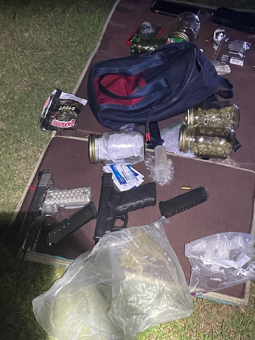 Photo of firearms and drugs on ground