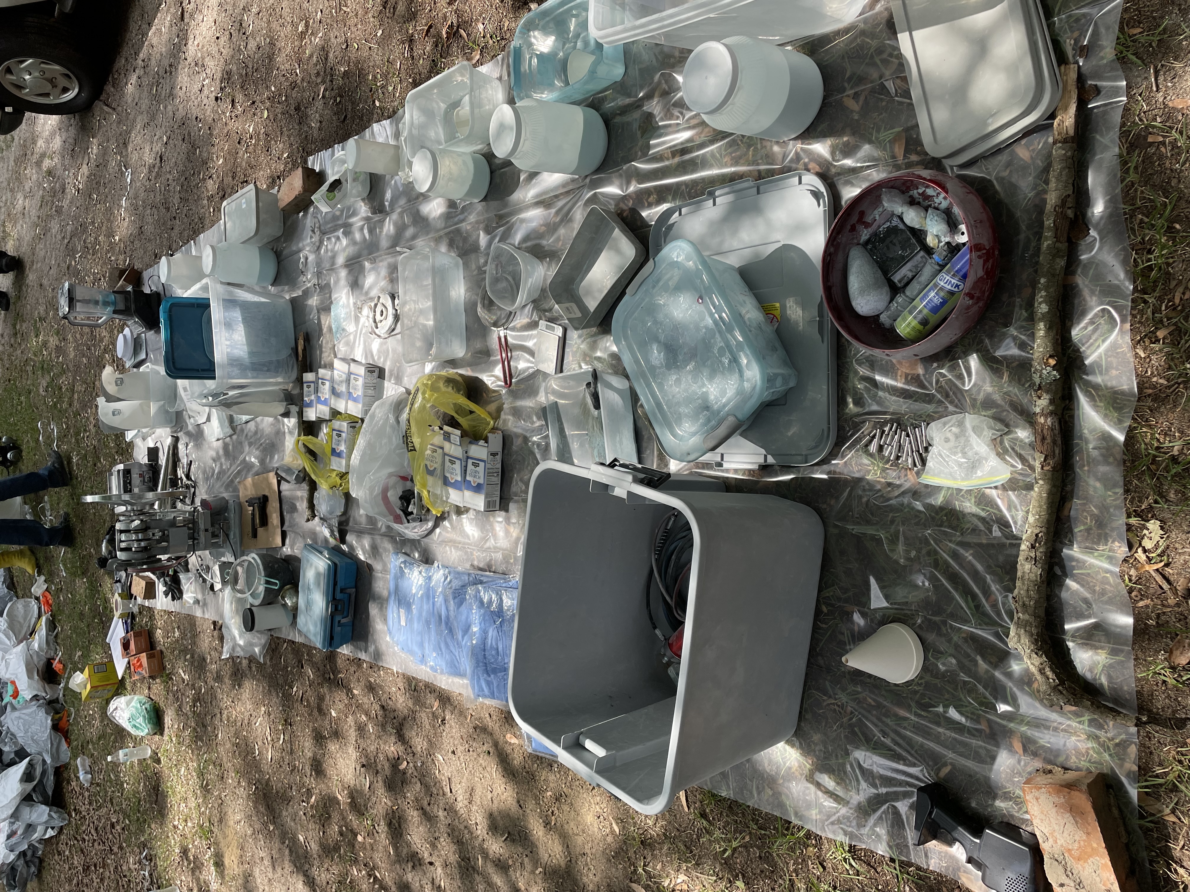 Photo of gray and blue containers on ground on top of clear plastic