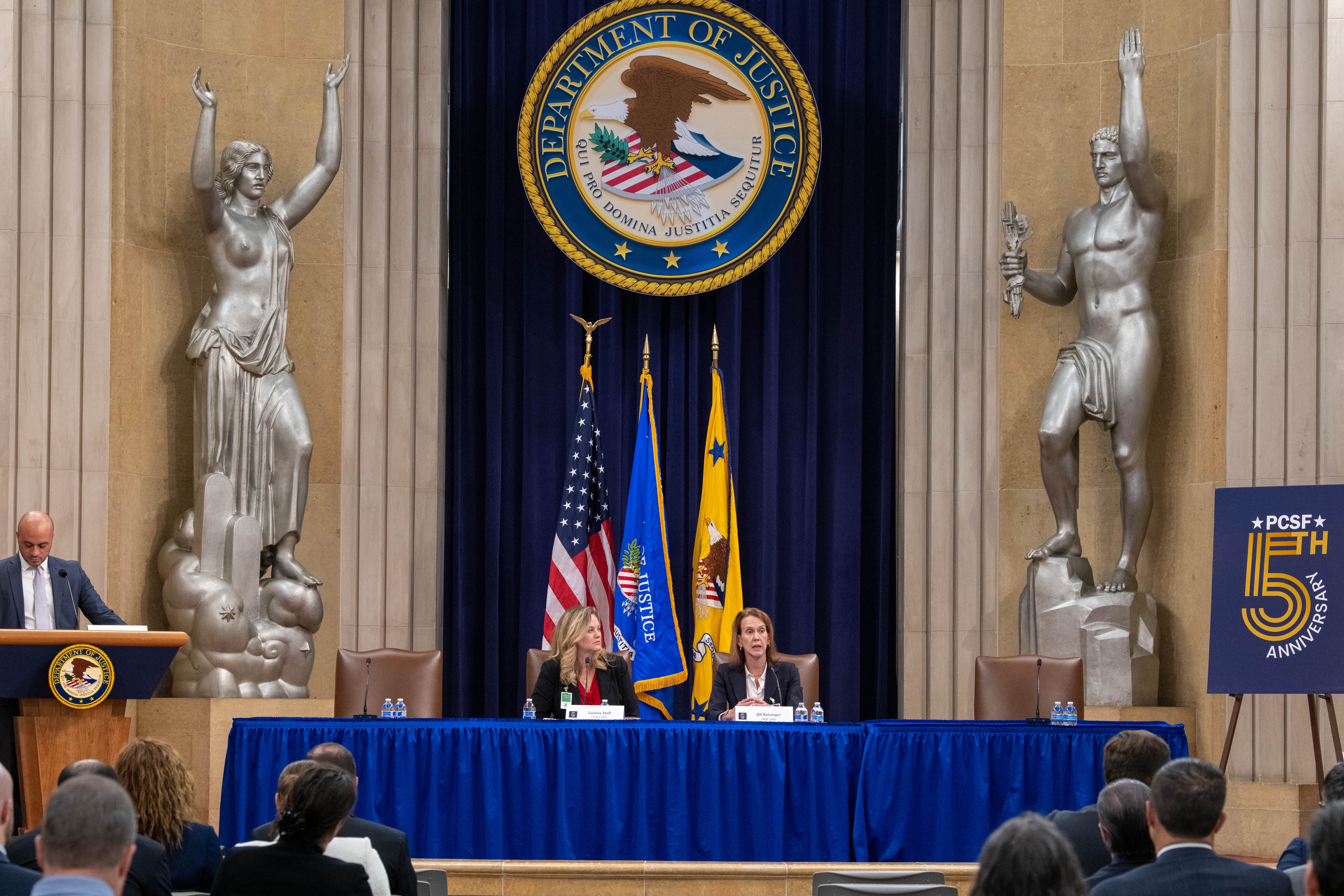 U.S. Postal Service Inspector General Tammy Hull and Acting Department of Commerce Inspector General Jill Baisinger speak during the Justice Department’s PCSF Fifth Anniversary