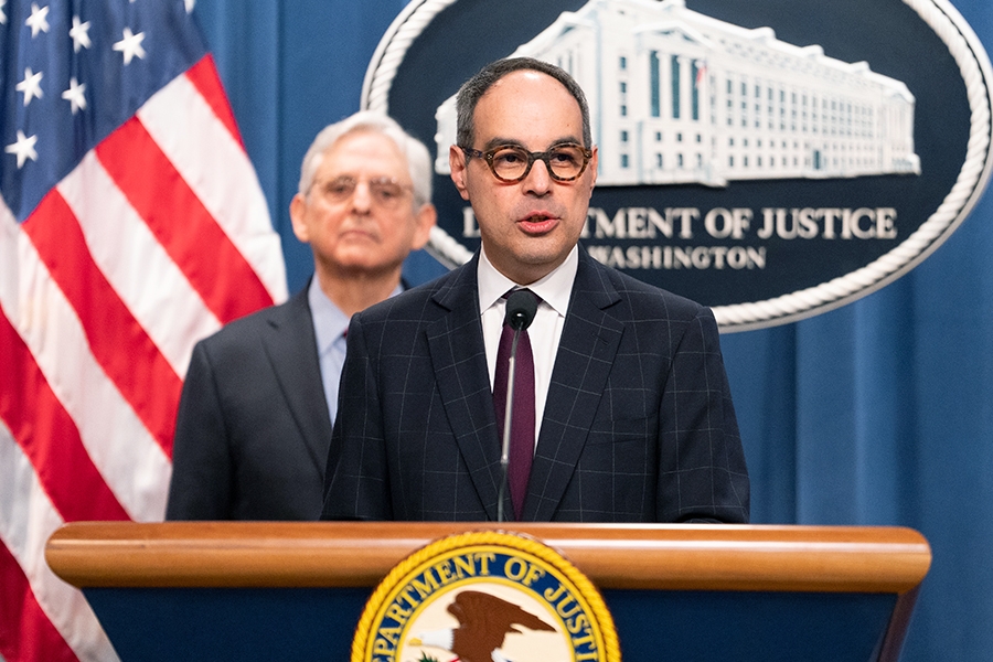 Assistant Attorney General Jonathan Kanter of the Justice Department’s Antitrust Division delivers remarks from a podium at the Department of Justice. He is joined by Department of Justice and federal government officials.