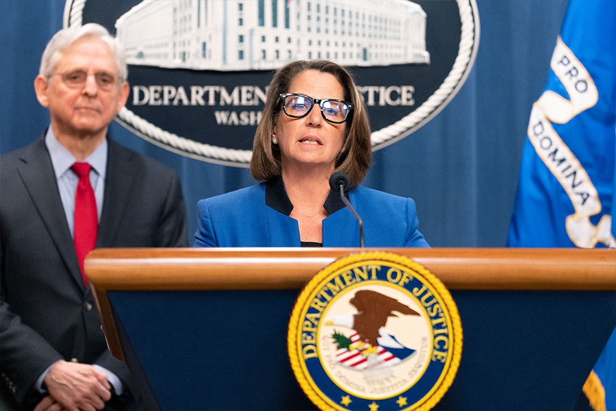Deputy Attorney General Lisa Monaco delivers remarks from a podium at the Department of Justice. She is joined by Department of Justice and federal government officials.