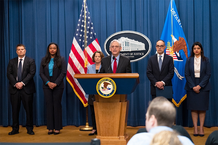 Attorney General Merrick B. Garland delivers remarks from a podium at the Department of Justice. He is joined by Department of Justice and federal government officials.