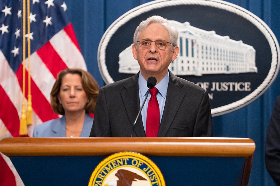 Attorney General Merrick B. Garland delivers remarks from a podium at the Department of Justice. He is joined by Department of Justice and federal government officials.