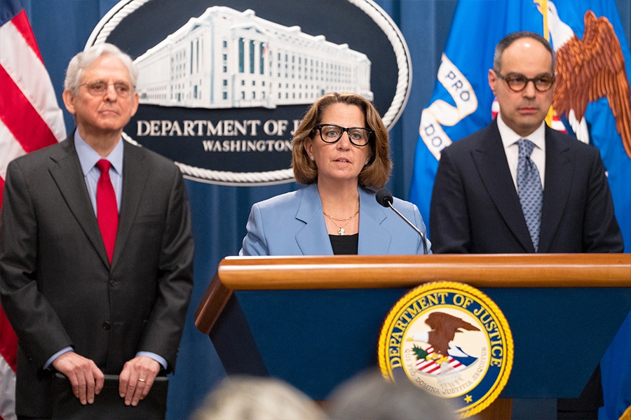 Deputy Attorney General Lisa Monaco delivers remarks from a podium at the Department of Justice. She is joined by Department of Justice and federal government officials.