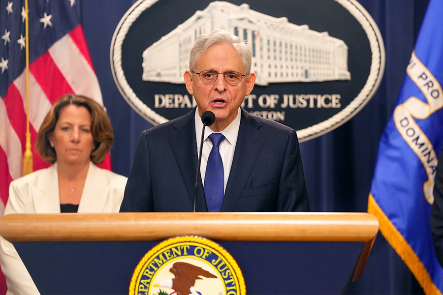 Attorney General Merrick B. Garland delivers remarks from a podium at the Department of Justice. He is joined by Department of Justice and federal government officials.