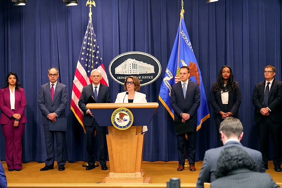 Deputy Attorney General Lisa Monaco delivers remarks from a podium at the Department of Justice. She is joined by Department of Justice and federal government officials.