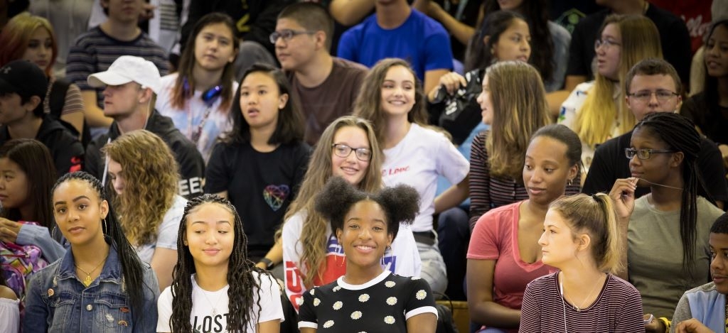 A diverse group of high school students sit on bleachers.