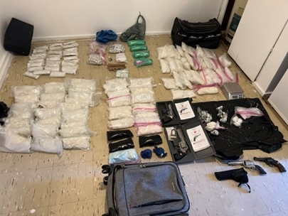 picture shows a large amount of seized drugs and guns 