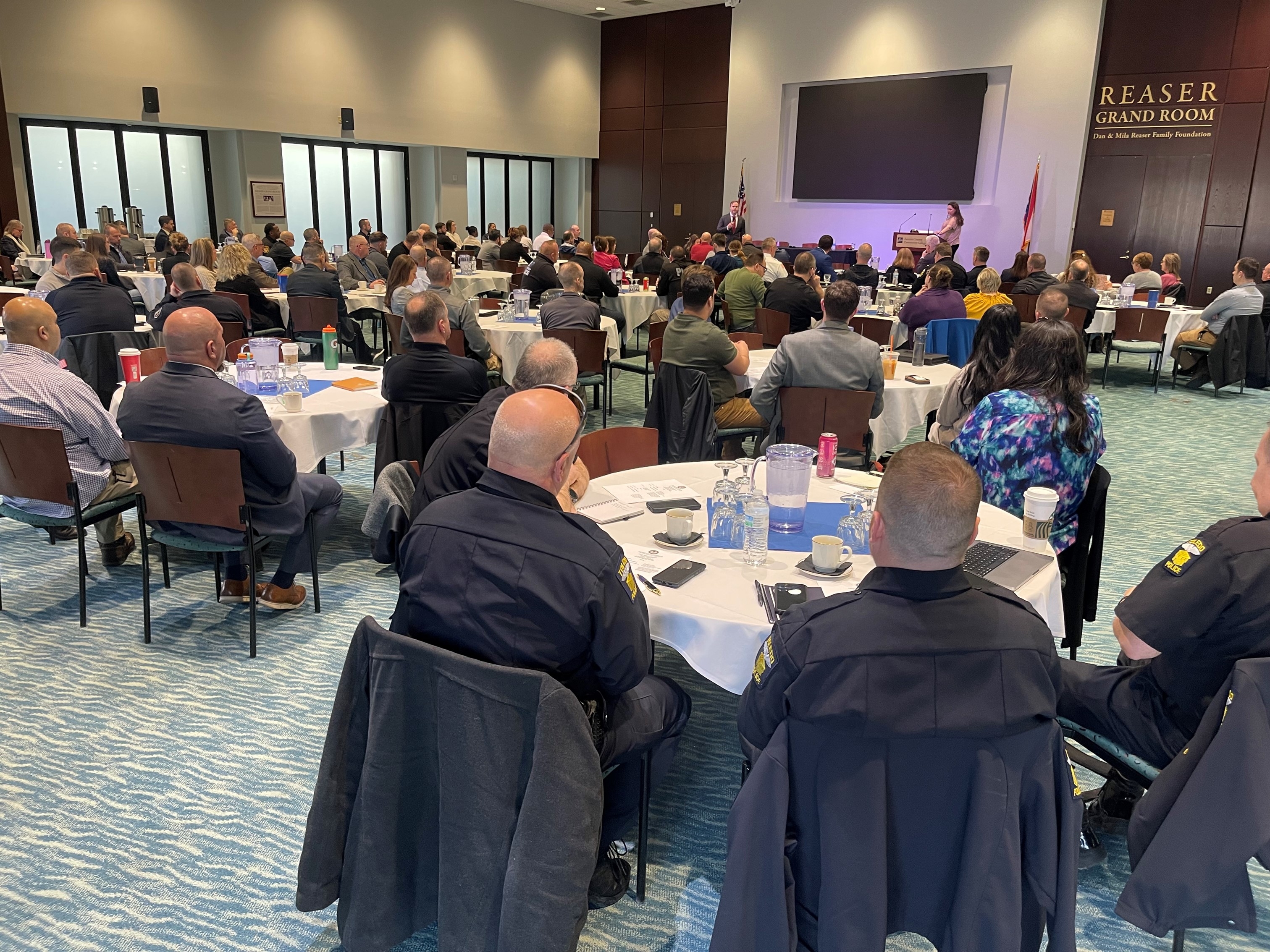 Attendees are seated in a large conference room at a violent crime consortium event.
