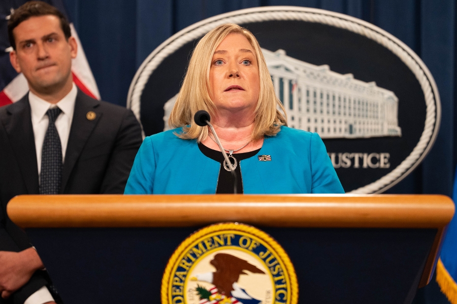 Juliet T. Hodgkins delivers remarks from a podium at the Department of Justice. She is joined by Department of Justice and federal government officials.