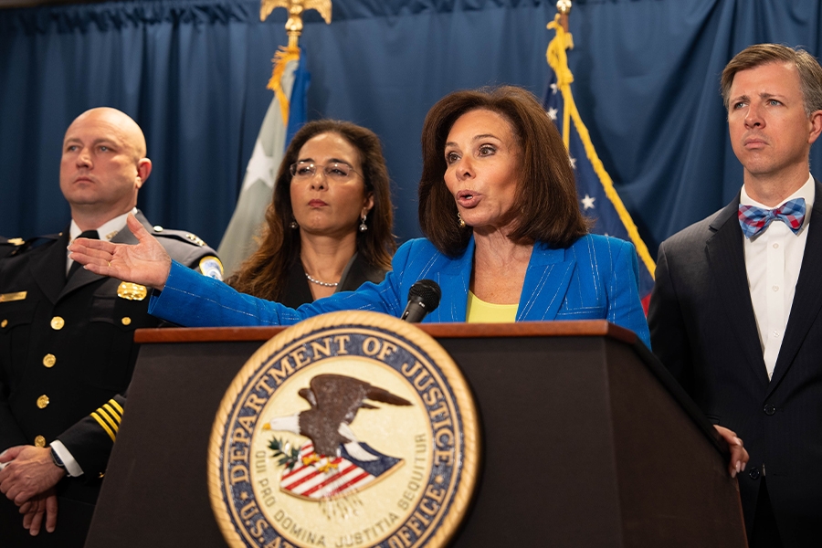 U.S. Attorney Jeanine F. Pirro for the District of Columbia delivers remarks from a podium at the U.S. Attorney’s Office for the District of Columbia. She is joined by federal and government officials.