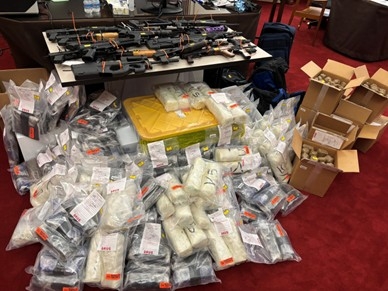 Image of piles of drugs and firearms seized by law enforcement