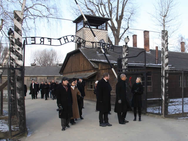 Attorney General Holder, accompanied by the Auschwitz-Birkenau Memorial and State Museum Director Piotr Cywinski, walk under the infamous entrance to the Auschwitz I concentration camp.