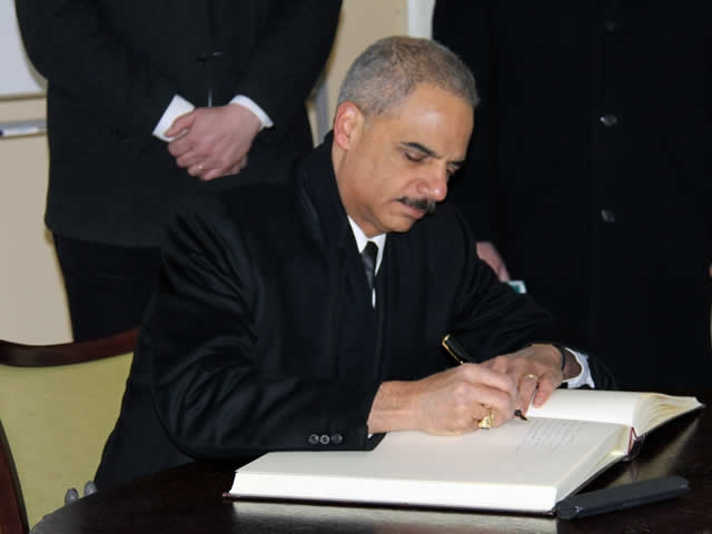 Attorney General Holder signs the guest book at the Auschwitz-Birkenau Memorial and State Museum.