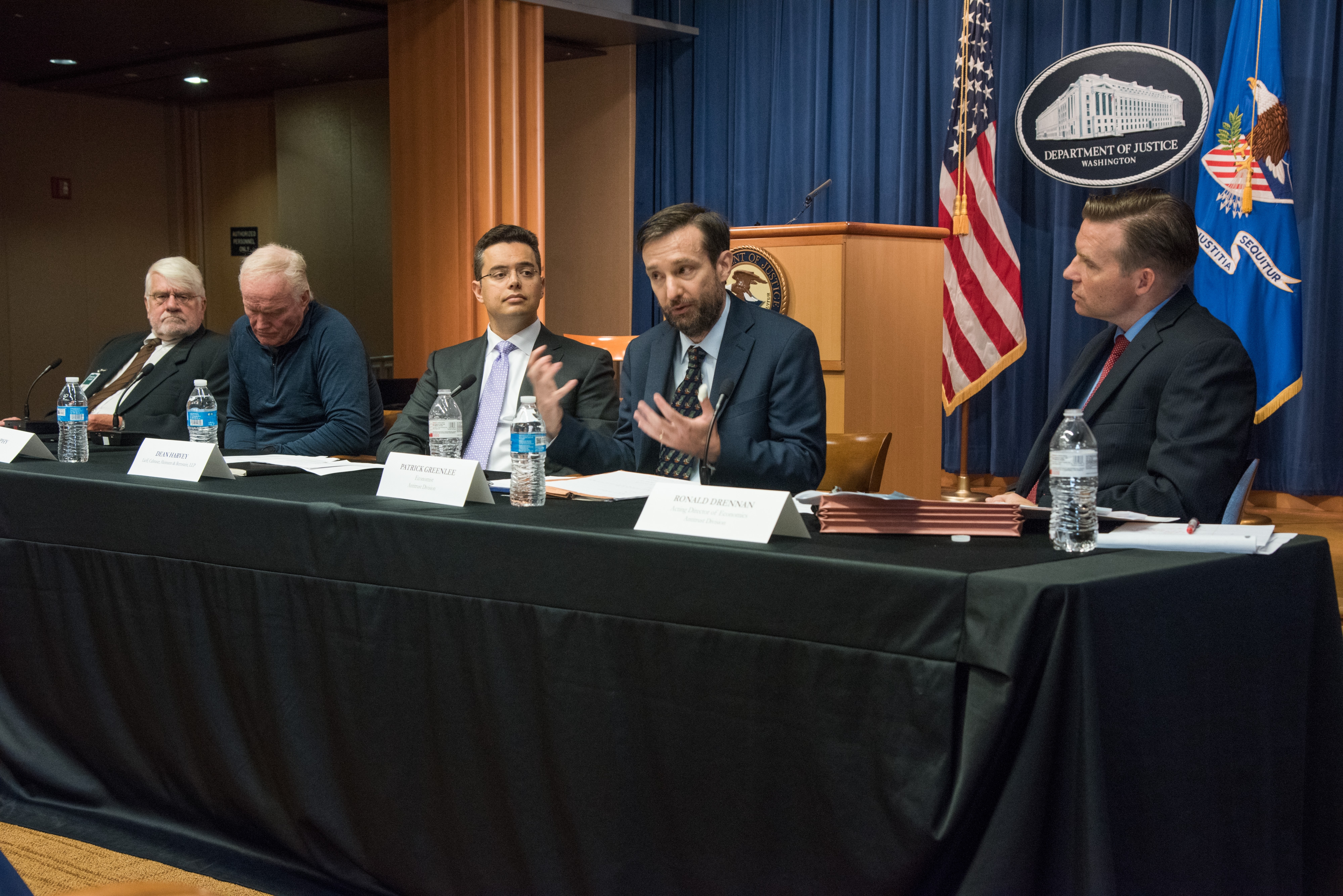 Panelists seated at a presentation table, listed from left to right: Orley Ashenfelter, Kevin Murphy, Dean Harvey, Patrick Greenlee (speaking), and Ronald Drennan