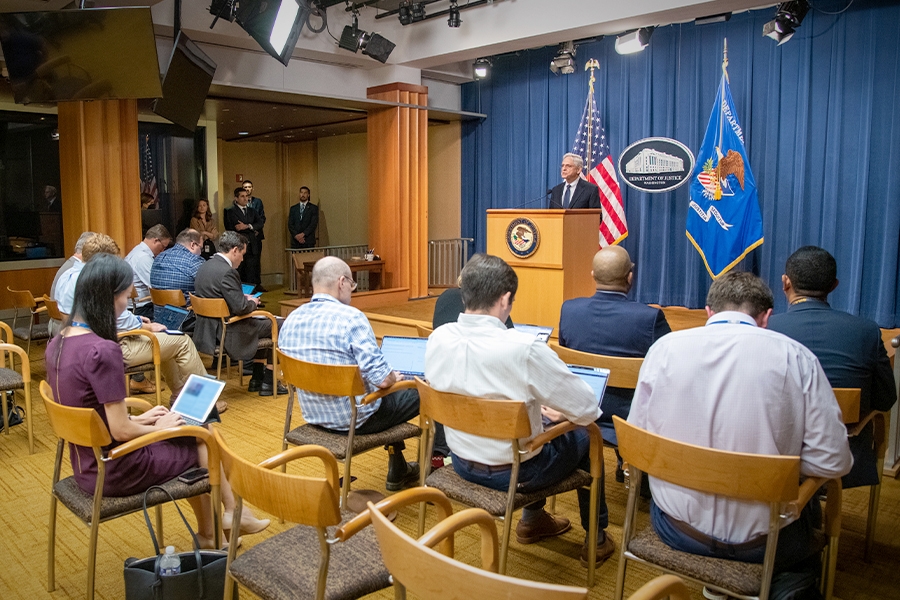 Attorney General Merrick B. Garland speaks to press and media at a podium bearing the Department of Justice seal.