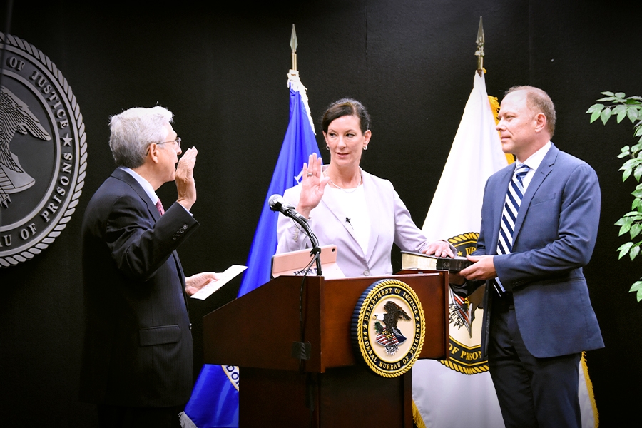 Attorney General Merrick B. Garland and Colette S. Peters hold up their right hands as the oath of office is taken. Ms. Peters has her left hand placed on her family bible.