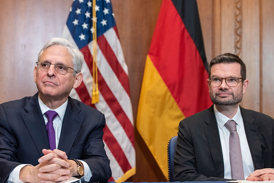 Attorney General Merrick B. Garland and the German Minister of Justice Dr. Marco Buschmann sit in front of the flag of the United States of America and the flag of Germany, respectively