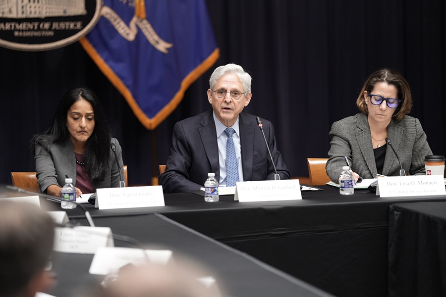 Attorney General Garland, Deputy Attorney General Monaco, and Associate Attorney General Gupta sit at a table during a meeting with law enforcement leaders.