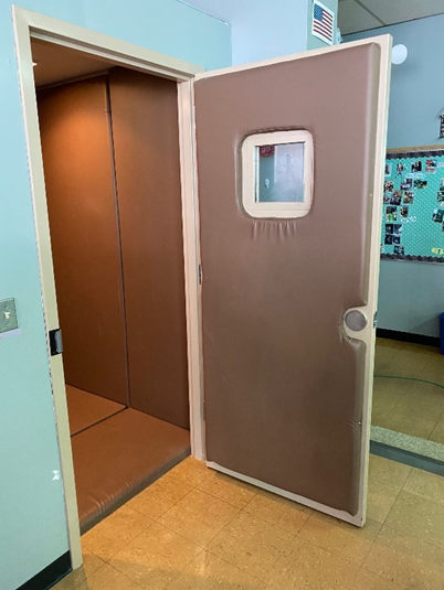 Photo displays a small, padded room, with a padded door.