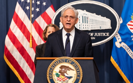 Attorney General Merrick B. Garland delivers remarks from a podium at the Department of Justice.