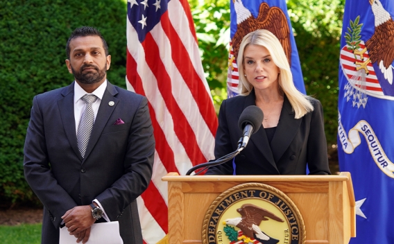 Attorney General Pamela Bondi delivers remarks from a podium at the Department of Justice. She is joined by FBI Director Kash Patel.