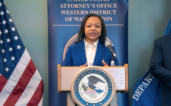 Assistant Attorney General for Civil Rights Kristen Clarke delivers remarks from a podium at the United States Attorney’s Office for the Western District of Washington.